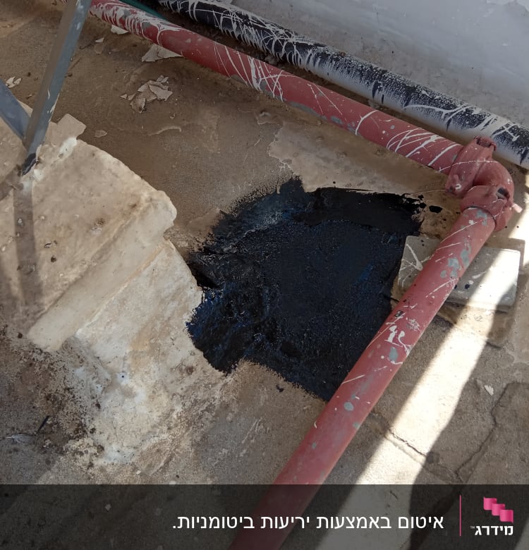 אזור אטום בזפת שחורה ליד צינור אדום